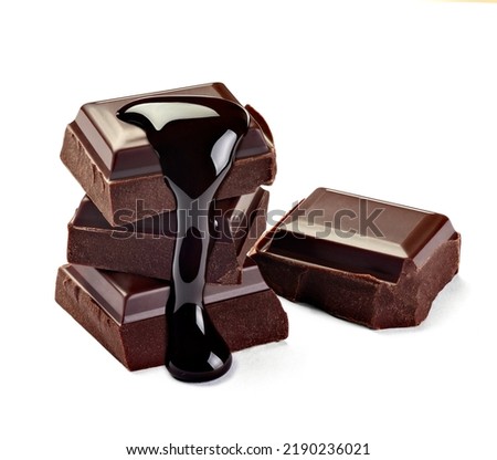close up of chocolate pieces stack and chocolate syrup on white background