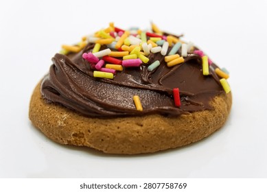 Close up of a Chocolate Spread Covered Mini Sponge Cake with Colourful Sugar Strands Sprinkled on Top 