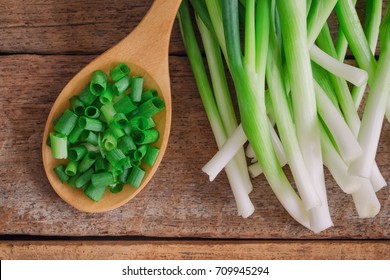 Close up chopped fresh spring onion on rustic wood table in top view flat lay with copy space. Prepare scallions for cooking. Food and vegetable concept for background or wallpaper.