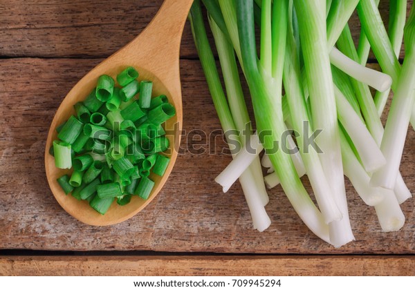 Close up
chopped fresh spring onion on rustic wood table in top view flat
lay with copy space. Prepare scallions for cooking. Food and
vegetable concept for background or
wallpaper.