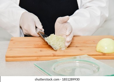 Close Up Of Chopped Onion Being Grabbed By An Out Of Focus Chef With The Help Of A Kitchen Knife. Safety And Cooking Concept.