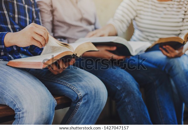 close up of christian group hold and opening bible\
page while reading and study bible together with friends in Sunday\
school class room