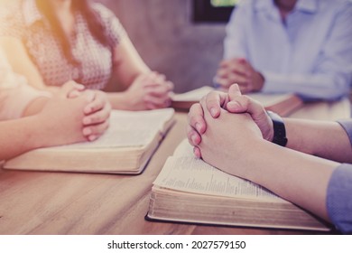 Close up of Christian groups are study bible and praying on the bible together around a wooden table in the home, Christian fellowship, or Cell group concept. devotional background with copy space. - Shutterstock ID 2027579150