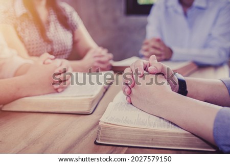 Close up of Christian groups are study bible and praying on the bible together around a wooden table in the home, Christian fellowship, or Cell group concept. devotional background with copy space.