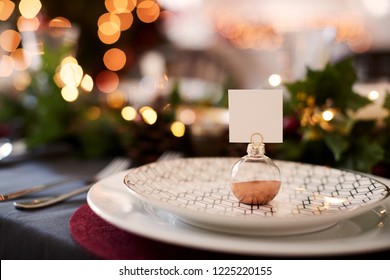 Close Up Of Christmas Table Setting With Bauble Name Card Holder Arranged On A Plate And Green And Red Table Decorations