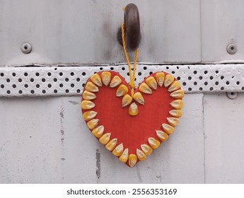 Close up of a christmas tree decoration, a red paper heart decorated with yellow corn grains. Happy ventine - Powered by Shutterstock