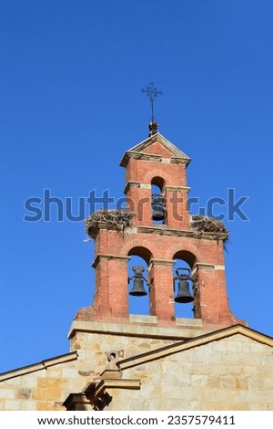 Close up of Church Bells Steeple with stork bird nests on clear blue sky day 