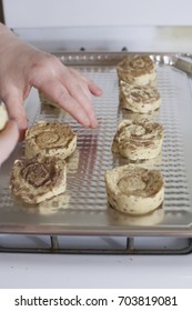 Close up of cinnamon rolls being placed on a cooking sheet