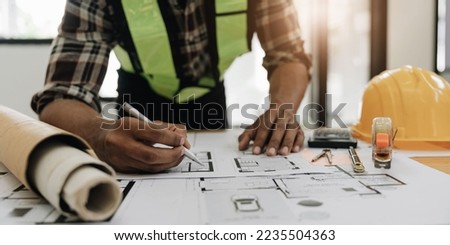 Close up of civil male engineer asian working on blueprint architectural project at construction site at desk in office. Stock photo © 