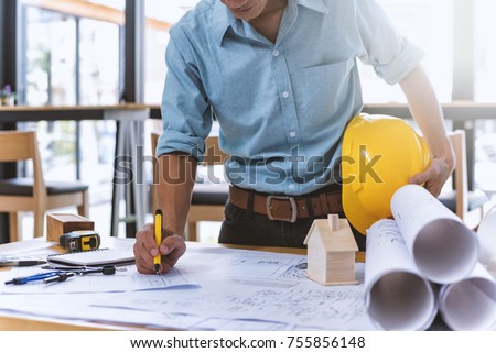 Close up of civil male engineer asian working on blueprint architectural project at construction site at desk in office. Stock photo © 