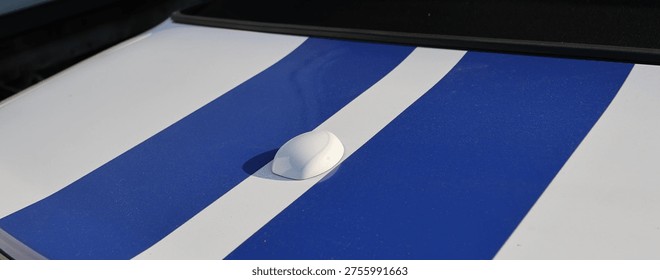 Close up of classic blue racing stripes on the rear trunk lid of a white convertible sports car