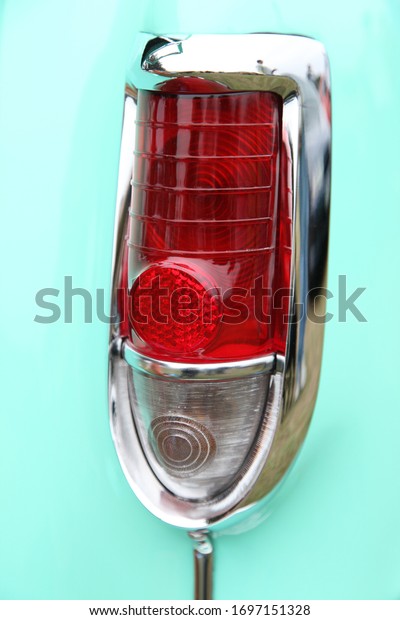Close up of a classic car rear light, including\
the brake light and blinkers. The vintage car is painted in bright\
aqua coloured paint.
