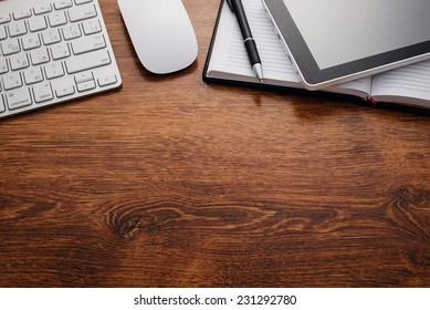 Close Up Clean Open Notebook And Electronic Devices Such As Keyboard, Mouse And Tablet, On Top Of Wooden Table With Copy Space Below For Texts.