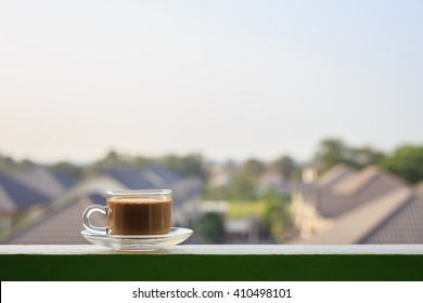 Close Up Clear Coffee Cup On Balcony And Blurred View Of Building