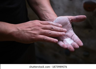 Close up of a climber man using liquid chalk magnesium preparing to climb indoor.
