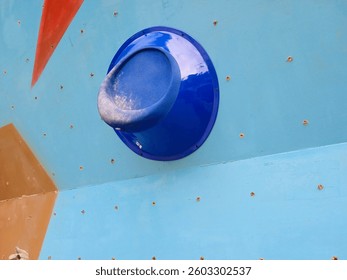 Close up of climbing wall holds and grips of varied shapes and sizes on blue outdoor climbing wall. Artificial climbing wall. Bouldering climbing wall - Powered by Shutterstock - Get 15% off with code: PIKWIZARD15