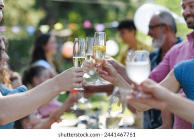 Close up of clinking glasses at summer garden party. Celebratory toast at the table. - Powered by Shutterstock