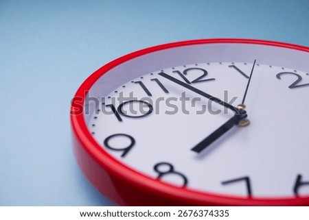 Close up clock hands of white red analog round wall clock face with blue background. Abstract deadline, last minute, in time, on time, time management and so on concept.