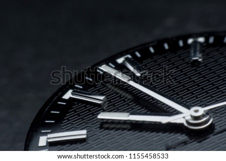 Close up clockwise on black clock face background. Wristwatch in retro style