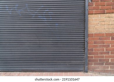 Cierre de la puerta de enrollado de metal cerrado en la pared de albañilería de ladrillo como concepto para la prevención de tiendas cerradas y robos