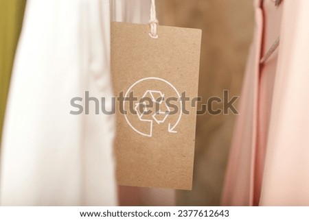 Close up of clothing tag with recycle icon. Recycling products concept. Zero waste, suistainale production, environment care and reuse concept.	