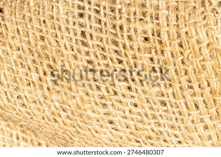 Close up of coarse linen canvas texture in warm light creating natural fabric background with rustic textile surface, organic material detail, and earthy neutral aesthetic backdrop