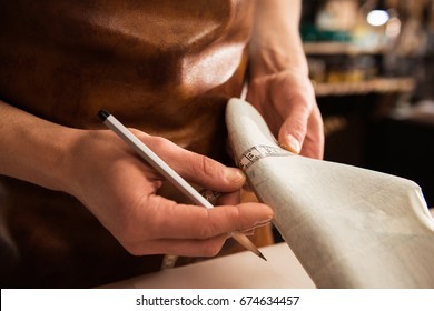 Close up of a cobbler doing measurments for a shoe with tape at his workshop - Powered by Shutterstock