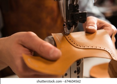 Close up of a cobbler stitching a part of the shoe at a workshop