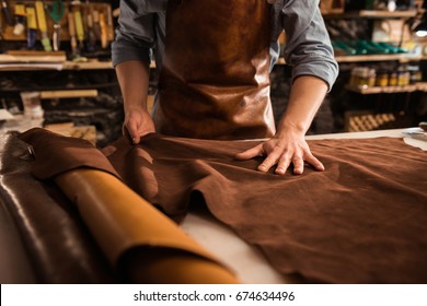 Close up of a cobbler working with leather textile at his workshop