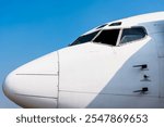 Close up of cockpit white large passenger airplane with blue sky stock photo. Side view.