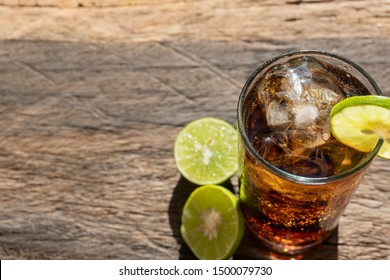 Close Up Cocktail In Glass With Ice Cola And Lemon. Cola On The Wood Floor. Soft Drink With Soda