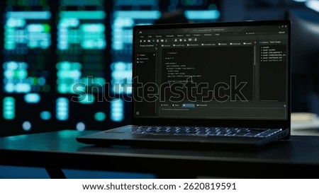 Close up of code running on laptop screen in data center used for managing gear energy consumption. Focus on notebook used by software developer in blurry background in server farm, camera A