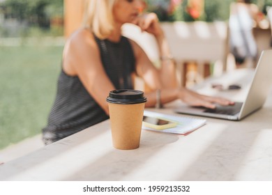 Close Up Coffe Cup. Adult Woman Typing At Laptop And Mobile Cell Phone Outside In Park. Thinking Senior Working And Drinking Coffee. Using Computer. Distance Learning Online Education And Shops.