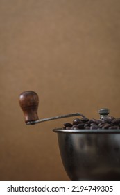 Close Up Of Coffee Beans In A Traditional Coffee Grinder. Brown Monochromatic Rustic Food Photo With Copy Space