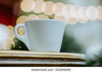 Close Up Of Coffee Cup On Outdoor Terrace Table With Bokeh Christmas Lights Background