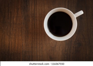 Close Up Of A Coffee Mug On A Dark Wooden Table. Shot From Above.