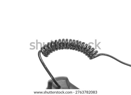 Close up of coiled black plastic cable showing spring structure. Telecommunication equipment connection wire. Flexible curly cord used for electronic devices and phones.
