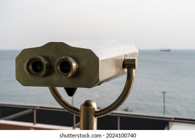 Close Up Of Coin Operated Binoculars Against Sea During Sunset