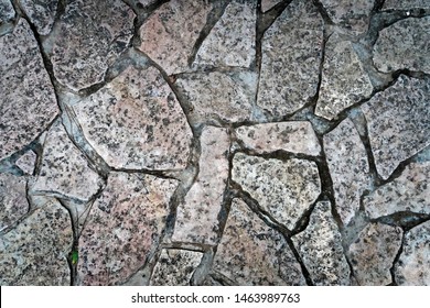 Close up of cold and wet stone path. Stone walk texture, background with cracked stone material. Abstract ancient dark granite walk. Exterior design natural materials. Ground shot from above