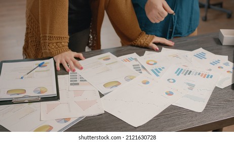 Close up of colleagues checking papers with data rate charts on table. People using information files to plan business project and presentation, working on startup organization development