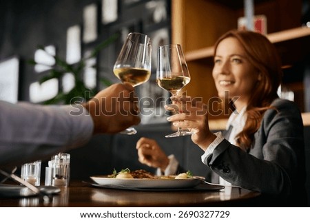 Close up of colleagues toasting while having business lunch in restaurant. 