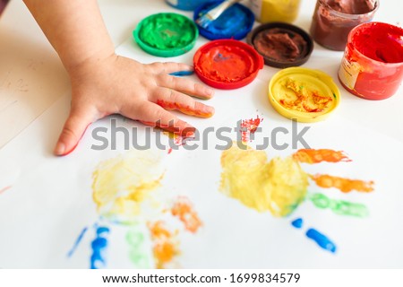 Close up of colored hand print on white background. Ideas for drawing with finger paints. Finger painting for kids. Little girl painting by finger hand paint color. Children development concept.