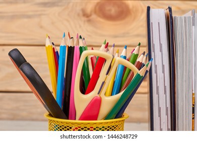 Close up colorful school supplies background. Books and metal holder with stationery items. Back to school concept.