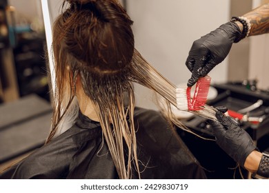 Close up of colorist dyes hair of woman with brush and foil in beauty salon - Powered by Shutterstock