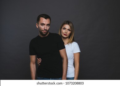 Close Up Colour Studio Portrait Of Stylish Young Couple, Pretty Woman Stands Behind Handsome Man, Against Plain Studio Background.