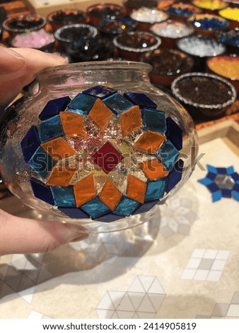close up of colourful pattern of Turkish mosaic tile art in progress sticking on lamp glass with material at the back.
