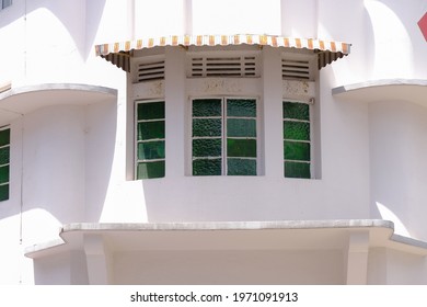 Close up of common windows with awning and vintage green panes, exterior view of old public housing in Tiong Bahru. White walls with curved architectural details inspired by art deco