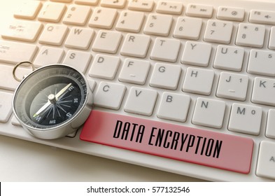 Close up of compass and word DATA ENCRYPTION on white keyboard.