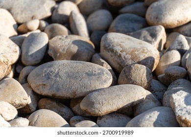 A close composition of smooth pebbles reveals wear from water and time. Light and shadow carve gentle contours.
