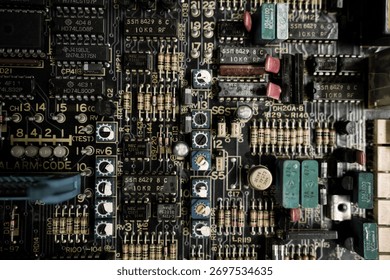 A close up of a computer board with many small components. The board is black and white with a few red and green components. Concept of complexity and technicality
